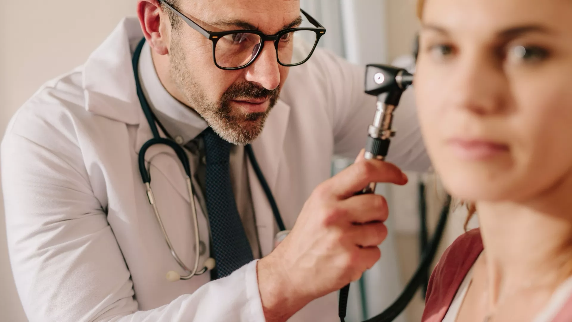 Doctor preparing to examine a woman’s ear with an otoscope
